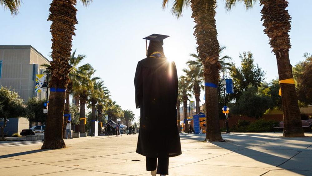 Photo of a College Graduate walking down the Paseo during the morning of Commencement